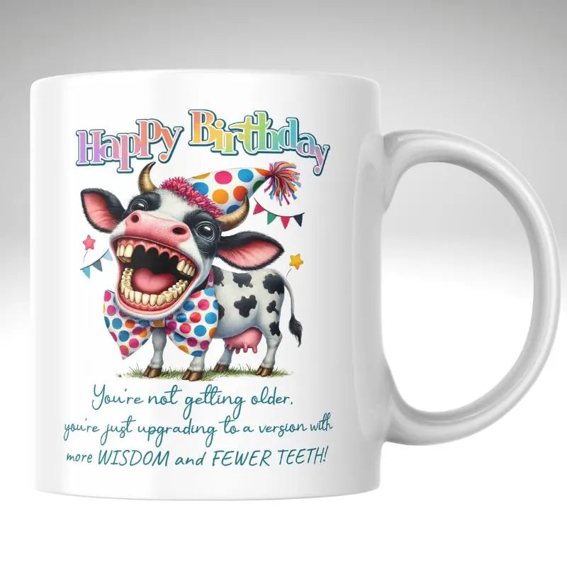 Funny Birthday Mug, You're Upgrading to Less Teeth. White mug with a colorful cow illustration and birthday message on a white background