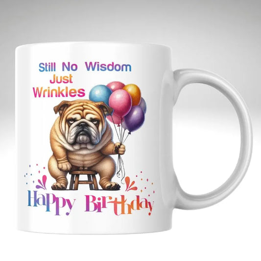 Still No Wisdom, Just Wrinkles Bulldog Birthday Mug. White mug with a cartoon bulldog holding balloons and birthday text on a white background